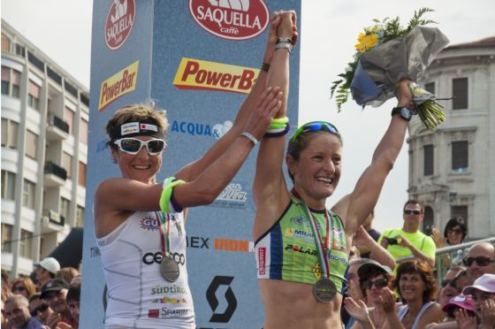 Edith Niederfriniger alza al cielo le braccia della vincitrice del 1° Ironman 70.3 Italy, Martina Dogana