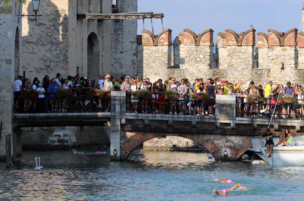 Il suggestivo passaggio degli atleti sotto il ponte levatoio durante frazione di nuoto dell'Oakley TriO Sirmione.